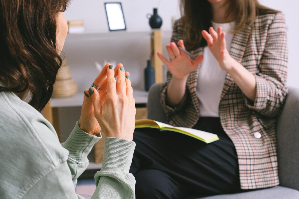 Two women sit across from each other having a discussion.
